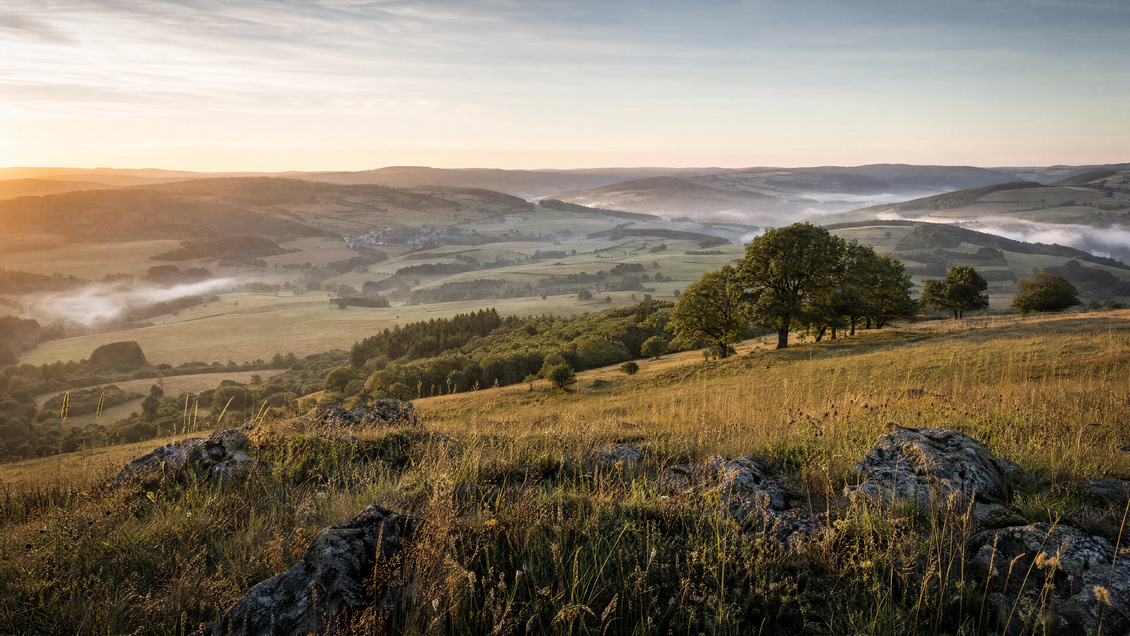 KI-generierte Landschaft mit Wiesenhängen, Waldinseln und leichtem Morgennebel